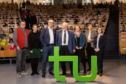Gäste der Veranstaltung in einem Gruppenbild hinter dem TU Logo
