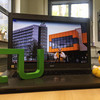 A laptop showing a video. In the foreground is the TU logo and a rubber duck.