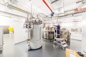 Ein Labor mit einem großen weißen Behälter für Kyrotechnik und einem Metallbehälter, ein Mann steht auf einer Leiter.