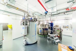 Ein Labor mit einem großen weißen Behälter für Kyrotechnik und einem Metallbehälter, ein Mann steht auf einer Leiter.