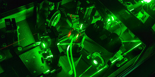 Eine Detailaufnahme eines Lasers im Labor in dunkel grünen Farben.